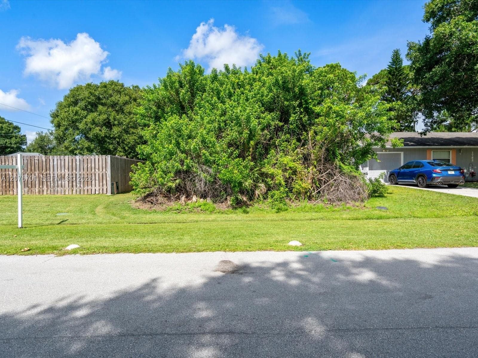 Part of the wooden fence is on the subject property, partially fenced across front, open and overgrown to the South side.